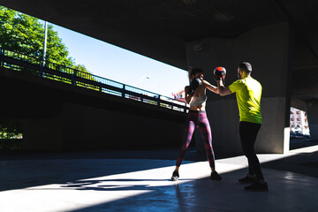 Fototapeta premium Spanish Woman Training Boxing with Coach Outdoors. Boxing Concept.