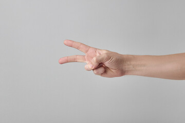 caucasian male person showing two fingers gesture. isolated over grey background.