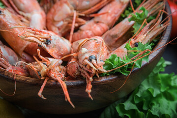 Large prawns, lying in a wooden dish. Seafood dish. Shrimp sauteed in a creamy sauce. Salad greens.