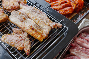 Top view of piece of barbecue pork belly and grilled steak on Electric Grill Griddle surrounded with raw meat on side.