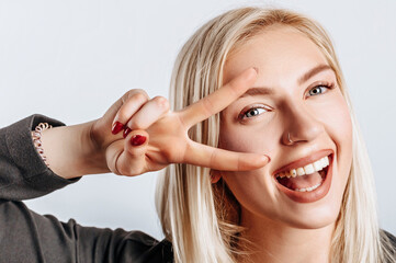 Hey smile you. Portrait of cheeky and cute glamor blond woman combed hair and jacket winking happily showing peace victory gesture as fooling around, being optimistic