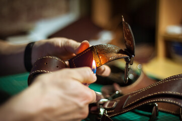 Production of leather products, close up. The view from the side. The master makes a leather product to order.