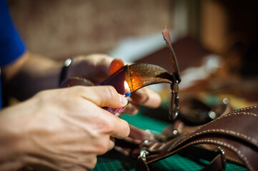 Production of leather products, close up. The view from the side. The master makes a leather product to order.