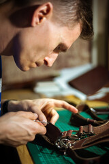 Production of leather products, close up. The view from the side. The master makes a leather product to order.