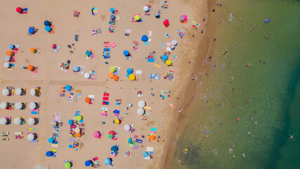 Fototapeta na wymiar Aerial view of sandy beach with tourists swimming in beautiful clear sea water in Madeira island.