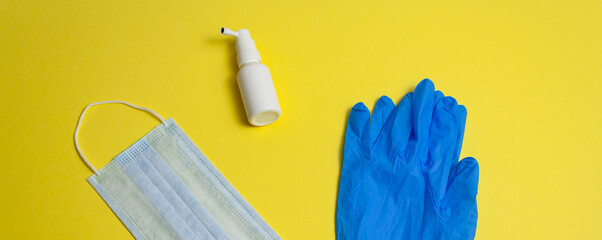 Concept of protective equipment kit against pandemic, coronavirus closeup, top view. Medical, hygiene face mask, antiseptic in bottle and blue gloves on yellow background isolated Banner for web site