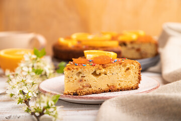 Orange cake and a cup of coffee on a white wooden background. Side view, selective focus.