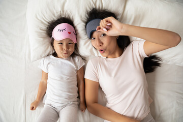 Above top view playful young refreshed vietnamese family wearing sleeping masks, feeling energetic...