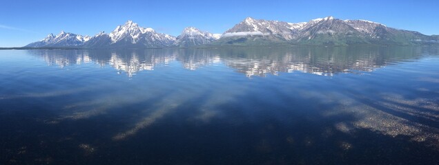 Panorama, crystal clear reflection of grand teton mountains in still peaceful lake