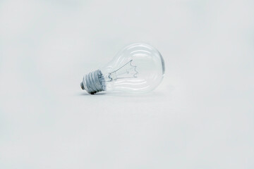 Incandescent light bulb lies on a light gray background. technology of the past, not reasonable consumption.