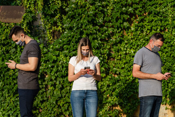 Fototapeta premium Front view caucasian man and woman using mobile phone - Modern communication online texting social network messaging - Men and woman with mask hold mobile phones - social distance new normal concept