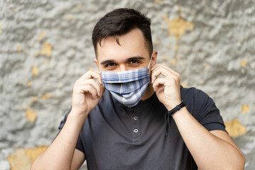 Portrait of adult caucasian man wearing protective mask putting on due to coronavirus outbreak - Young modern male social distance virus prevention - Front view in day outdoor - The new normal concept