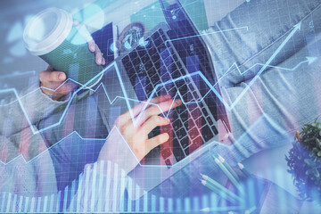 Double exposure of woman hands typing on computer and forex chart hologram drawing. Stock market...