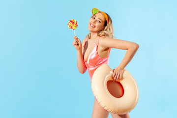 Portrait of lovely carefree beautiful woman in swimsuit holding rubber ring and sweet lollipop...