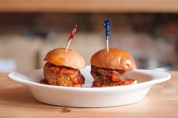 mini beef hamburger burger sliders with tomato sauce on brioche buns with toothpicks on a white...