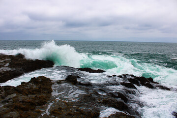 waves breaking on the rocks at the beach on a cloudy day