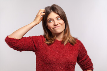 Not sure! Portrait of clueless uncertain girl in shaggy sweater scratching head, feeling confused...