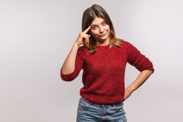 Insane idea! Portrait of girl in shaggy sweater makes stupid gesture with finger near head, out of mind, reckless expression, accusing crazy dumb plan. indoor studio shot isolated on gray background