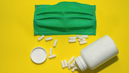 Scattered tablets,medical capsules,treatment tablets on a yellow background,the jar is white...