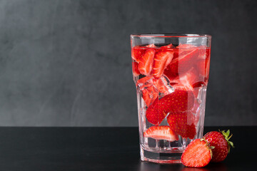 Ice drink with strawberries on black background. Summer berry lemonade. Place for text.