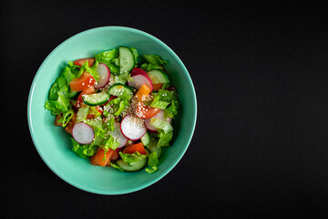 Seasonal vegetable salad from organic farm products on gray background. Mix of tomatoes, cucumbers and radishes.