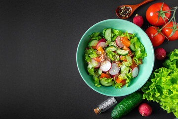 Fresh vegetable salad in a ceramic bowl on gray background. Seasonal summer dish of tomatoes, cucumbers and radishes.
