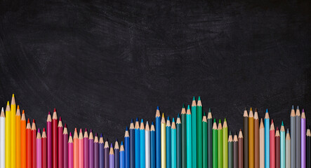 Wave border of colorful wooden pencils on a blank blackboard, back to school concept.