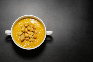 Pumpkin cream soup with crackers on a dark background