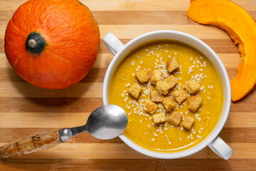 Autumn pumpkin soup with sesame seeds on a wooden background