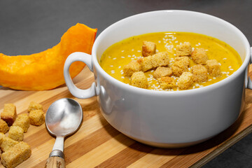 Autumn pumpkin soup with sesame seeds on a wooden background
