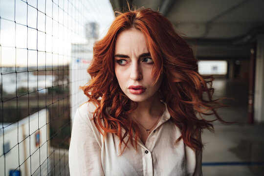 Portrait Of Frowning Caucasian Girl With Long Elegant Red Hairs. Frightened Millennial Female Model And Looking To Side.