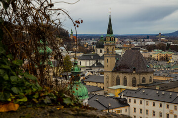 Fototapeta na wymiar Austria Salzburg moody Europe city landmark view catholic cathedral tower and gray old buildings from above top view point in rainy autumn day