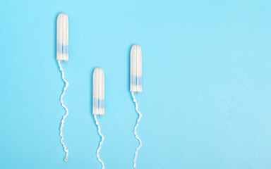 Three Menstrual tampons on a blue background. Menstruation cycle. Hygiene and protection. Disposable tampon. PMS