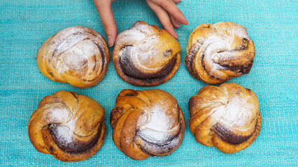 Top view of womens hand holding a sweet bun. There are more buns nearby. Bakery concept. Space for text.