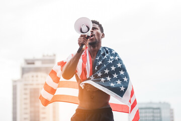 african american man with usa flag shouting into a megaphone in protest, black lives metter