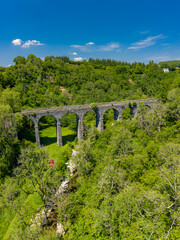 Aerial view of a small tenting camping in a rural valley underneath an old, victorian viaduct (Pontsarn, South Wales, UK)