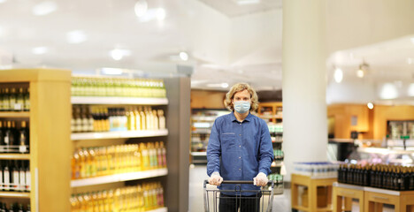 Fototapeta na wymiar Supermarket shopping, face mask and gloves,Young man shopping in supermarket, reading product information