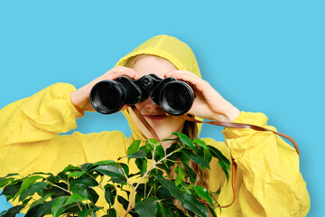 A Caucasian little girl in a yellow jacket looks through large binoculars. Studio isolated...