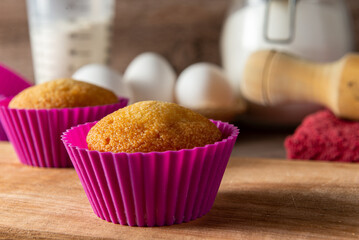 Muffins caseros en molde colorido, con sus ingredientes de fondo para prepararlos,  con foco...