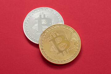Gold and silver bitcoin isolated on the red background.