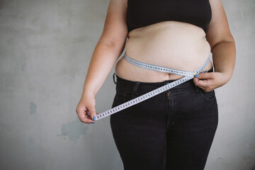 Overweight woman measuring waist with measure tape, close up image. Weight loss, motivation, fat...