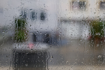 Close up and macro view of raining water drop on glass window and blur background of raining city environment. 