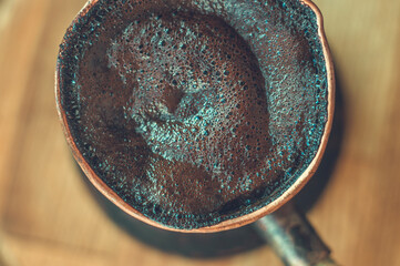 Natural coffee with thick foam, brewed in a copper cezve in the classical way, on a wooden...