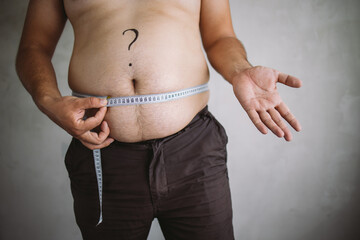 Overweight man measuring waist with measure tape, close up image. Weight loss, motivation, fat...