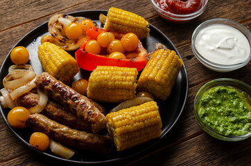 Grilled bbq sausages with vegetables, spices and three sau e on wooden