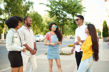 Diverse Group Young People Bonding Outdoors Concept. Communication of friends of different races on the background of the city and the street