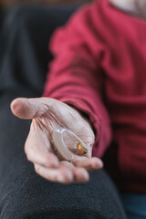 elderly person's hand holding hearing aid