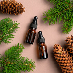 Brown glass dropper bottles mockup with pine tree branches and cones. Natural organic cosmetics, conifer essential oils. Flat lay, top view.