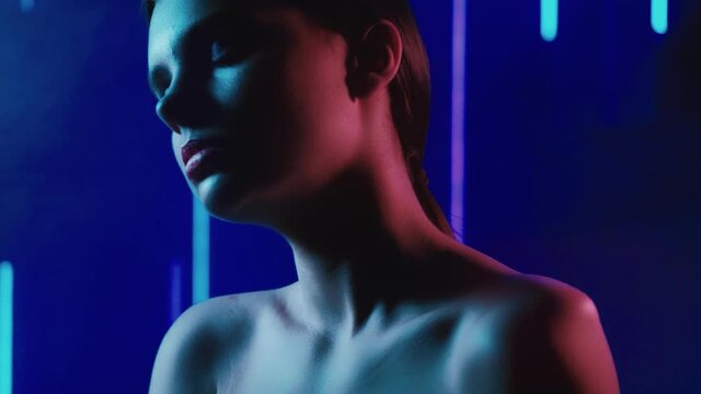 Colored light portrait. Sensual tranquility. Woman with bare shoulders daydreaming in neon smoke glow.