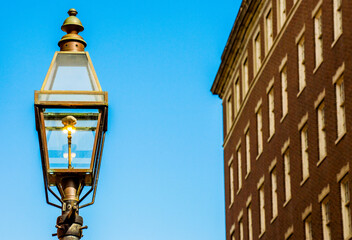 a vintage colonial street lantern near a classic brick building in Boston, Massachusetts at dusk